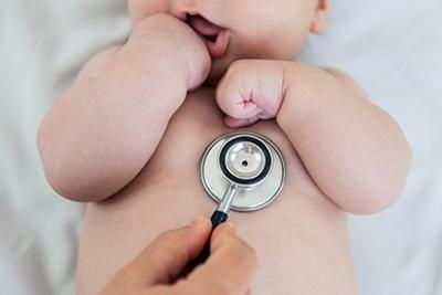 Newborn baby with stethoscope in chest.