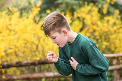 Young child coughing from asthma triggered by pollen