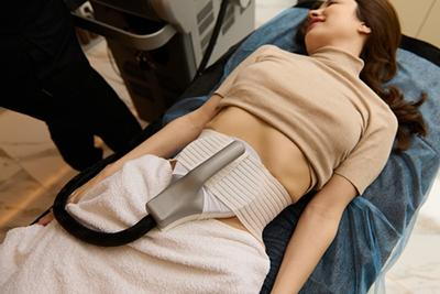 Female client during Emsculpt session targeting abdominal muscles in Katy, TX.