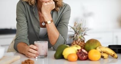 Smiling woman with smoothie and fruits promoting good gut health