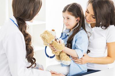 Doctor with young girl playing with her toys beside her mother