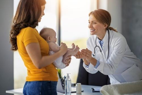 Mother holding her newborn baby during a pediatric visit.