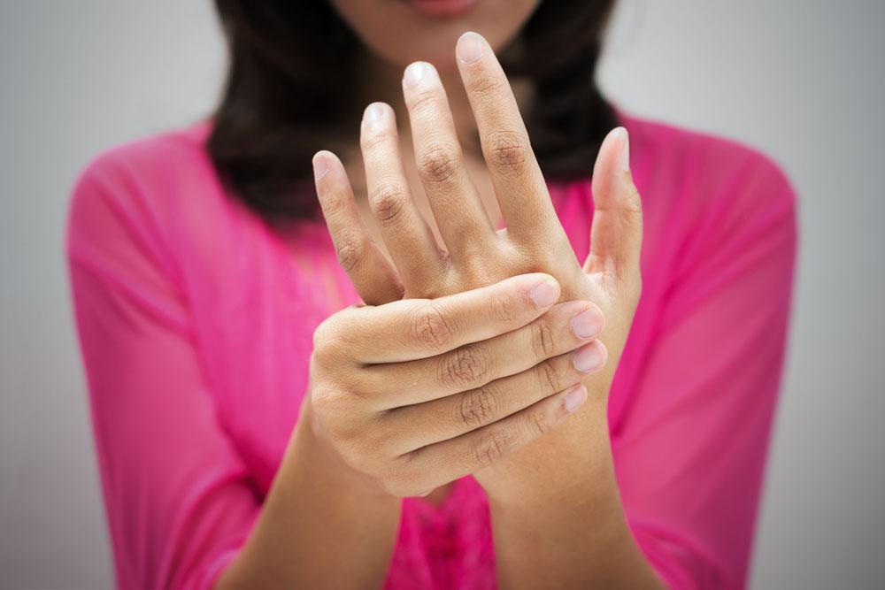 woman holding her hand because of tingling in fingers and numbness in hand