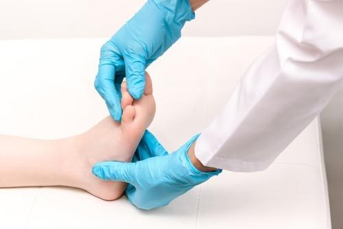 A podiatrist examining a child's foot to assess pain or discomfort.