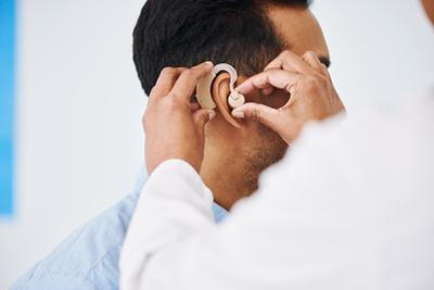 Doctor put the hearing aid in the man on climic.