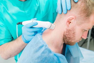 Man undergoing laser treatment for neck pain with a chiropractor.