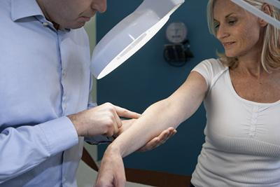 Dermatologist-examines-a-woman's-arm-for-skin-health.