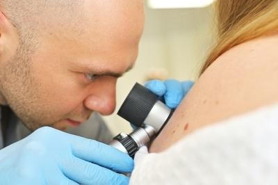 Doctor use a magnifying tools to examin patient skin.
