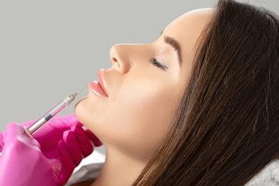 Dermatologist performing lip filler injection on female client