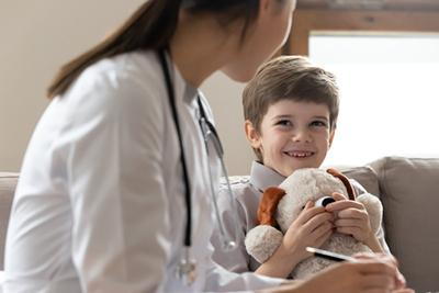 Smiling-boy-talking-to-doctor-with-a-teddy-bear-in-his-hand.
