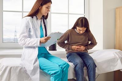 Pediatrician examining girl with stomach ache