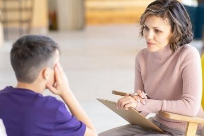 Therapist talking to a young boy on study room