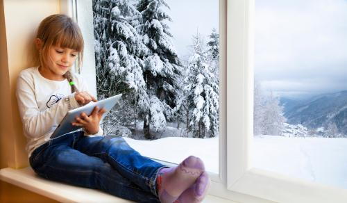 Young girl using tablet near window on cold day