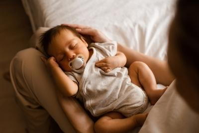 Mother taking care of her baby in her lap on bed