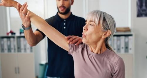 Chiropractor assisting a senior patient with mobility improvement during treatment