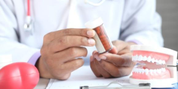 Close up of a dentist holding a bottle of medication at a desk