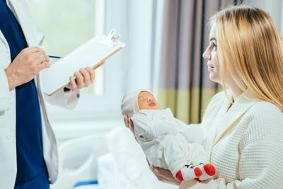 Doctor with notes talking to mother with baby on hand.