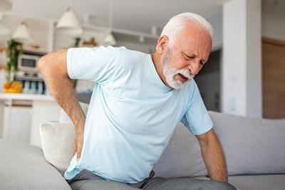 Senior man suffering from back pain on sofa