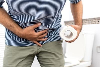 Person-holding-stomach-and-toilet-paper-in-bathroom.