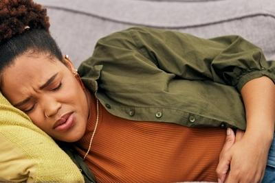 Woman Diagnose with IBS lying down in sofa.