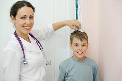 Smiling-doctor-measure-the-height-of-a-kid-in-clinic.