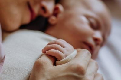 Mother pampering her newborn child on bed