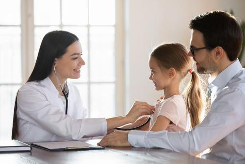 A child and father attending a well-child checkup with a pediatrician.