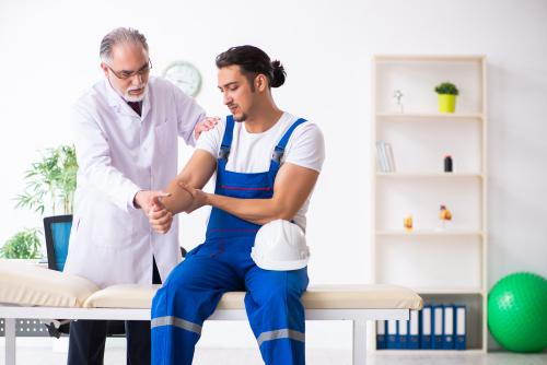 Worker’s comp injury patient discussing elbow pain with a chiropractor