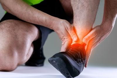 Runner holding his ankle in pain highlights in red.