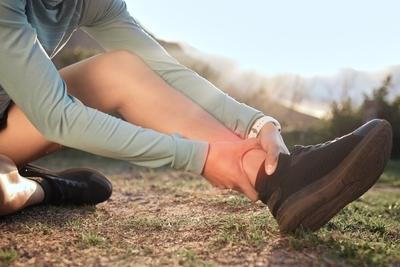 Person holding foot in pain outdoor.