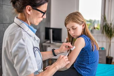 Doctor giving so shots to a young girl on clinic
