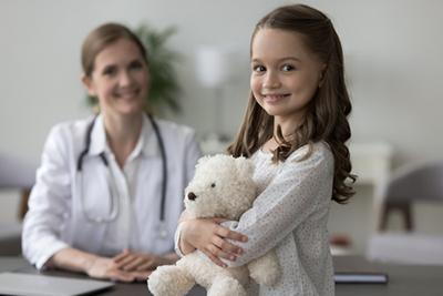 Child-Preparing-for-Her-Physical-Exam-with-Children's-Doctor-at-the-Background