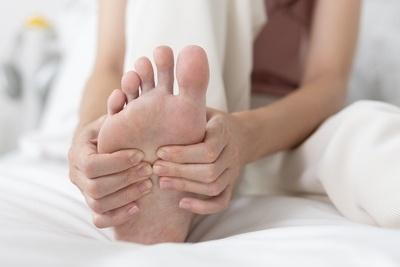 Person on bed suffering from foot pain holding it
