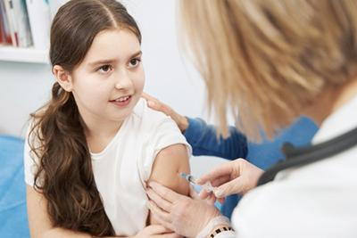 Young girl receiving childhood vaccination shot from doctor