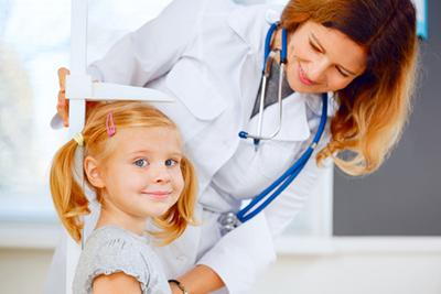 Young girl looking in camera while the doctor check her.