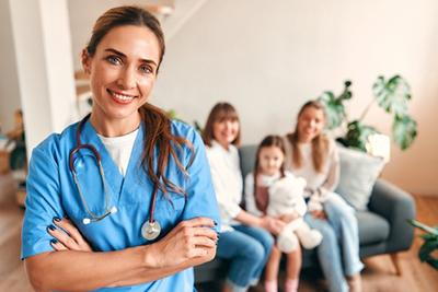 Female family medicine doctor posing in clinic with family in background