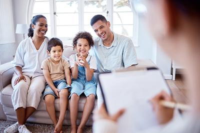 Family talking to a doctor with notes sitting on sofa