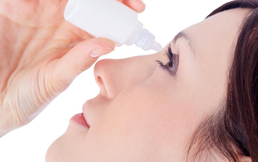 a close-up of a person applying eye drops