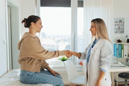 Young woman shaking hands with the doctor on clinic.