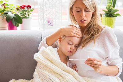 Mom using thermometer to check sick daughter’s fever