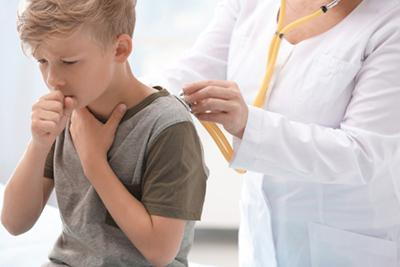 Doctor checking the young boy with cough on clinic