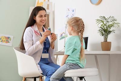 Child practicing how to use an inhaler under pediatrician’s supervision.