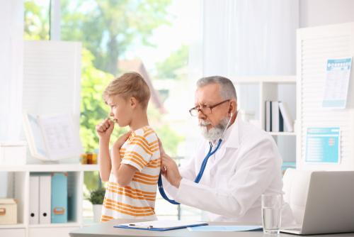 Pediatrician checking a child's breathing while the child coughs during an asthma evaluation