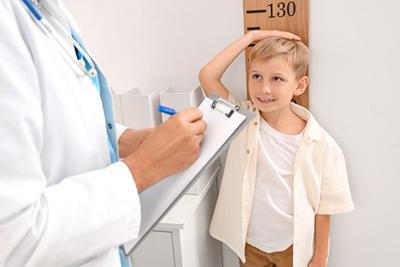 Family physician assessing physical development of child using height measurement tool