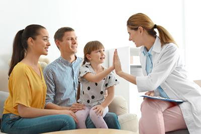 Doctor giving a high 5 in a young girl with her parents