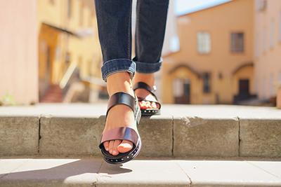 Close-up of woman’s feet in sandals stepping down outdoor stairs