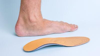 Orthotic inserts displayed beside flat feet