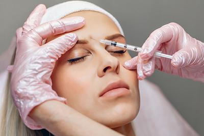 Womans face with Botox injection by the doctor.