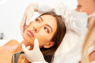 Doctor checking the condition of skin in womans face.