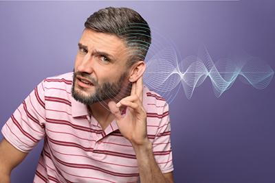Male experiencing hearing difficulties, depicted on purple backdrop